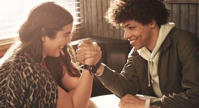 frau mit fossil julianna hr smartwatch am handgelenk beim armdruecken gegen mann frau mit fossil julianna hr smartwatch am handgelenk beim armdruecken gegen mann
