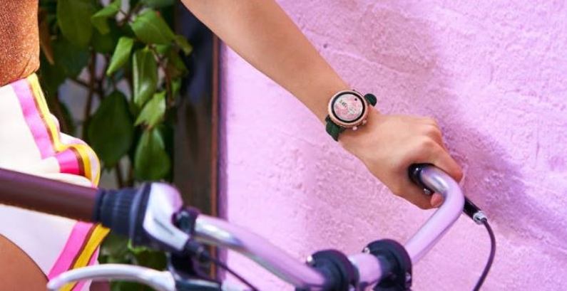 Dame mit Kate Spade New York Sport Smartwatch am Handgelenk auf Fahrrad Dame mit Kate Spade New York Sport Smartwatch am Handgelenk auf Fahrrad